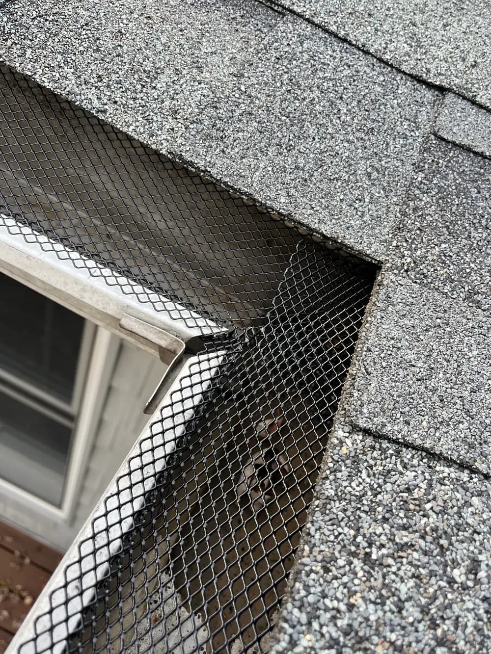 Mesh gutter guard cut and fitted into the inside corner where a dormer meets the main roof
